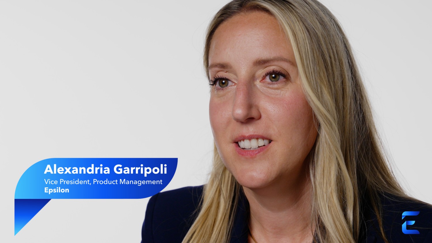 Alexandria Garripoli is framed in a side profile shot against a white background. Her name and title appear in a lower third graphic. She is wearing a blue blazer.